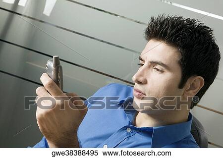 Close-up of a young man holding a mobile phone View Large Photo Image Stock Photography - Close-up of a young man holding a mobile phone. Fotosearch