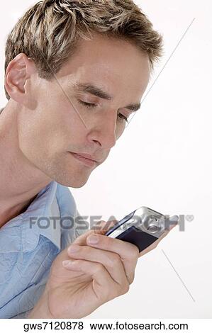 Stock Photo - Close-up of a young man looking at a mobile phone. Fotosearch