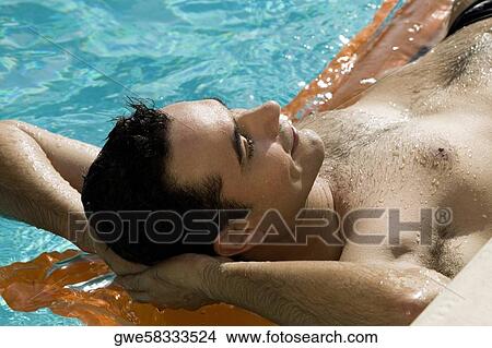 Picture - Close-up of a young man lying on a raft in a swimming pool. Fotosearch