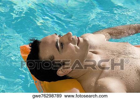 Close-up of a young man lying on a raft in a swimming pool View Large Photo Image Stock Photo - Close-up of a young man lying on a raft in a swimming pool. Fotosearch