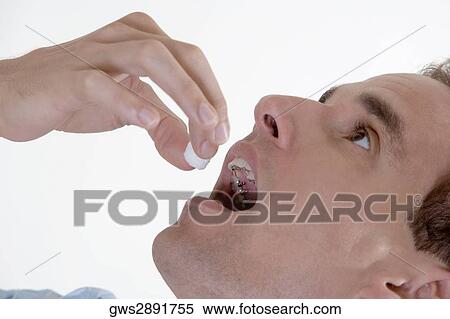 Stock Photography - Close-up of a young man putting candy in his mouth. Fotosearch