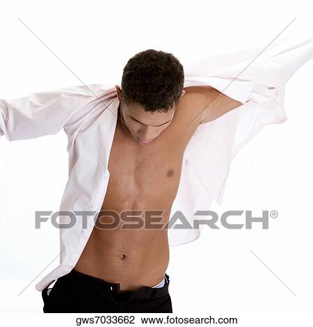 Stock Image - Close-up of a young man putting on a shirt. Fotosearch
