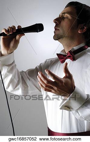 Close-up of a young man singing into a microphone View Large Photo Image Stock Image - Close-up of a young man singing into a microphone. Fotosearch