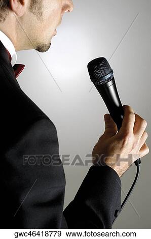 Stock Photo - Close-up of a young man singing into a microphone. Fotosearch