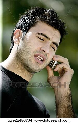 Close-up of a young man talking on a mobile phone View Large Photo Image Picture - Close-up of a young man talking on a mobile phone. Fotosearch