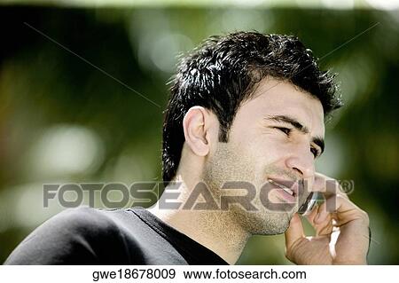 Close-up of a young man talking on a mobile phone View Large Photo Image Stock Photo - Close-up of a young man talking on a mobile phone. Fotosearch