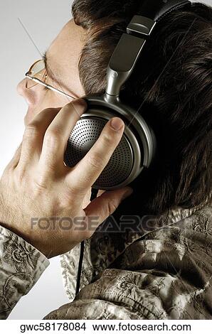 Picture - Close-up of a young man wearing headphones and listening to music. Fotosearch