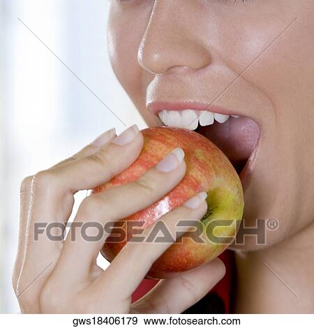 Close-up of a young woman biting an apple View Large Photo Image Stock Photo - Close-up of a young woman biting an apple. Fotosearch