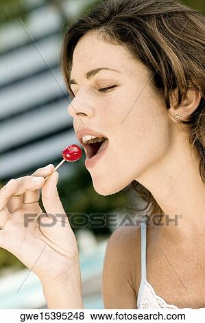 Stock Photo - Close-up of a young woman eating a cherry. Fotosearch