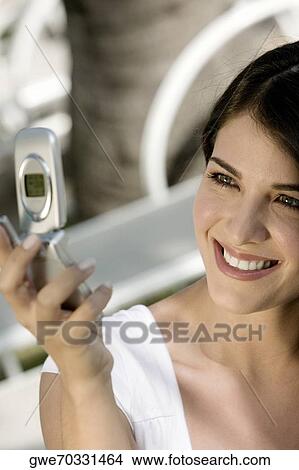 Close-up of a young woman holding a mobile phone View Large Photo Image Picture - Close-up of a young woman holding a mobile phone. Fotosearch