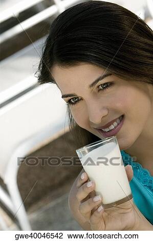 Close-up of a young woman holding a glass of milk View Large Photo Image Stock Image - Close-up of a young woman holding a glass of milk. Fotosearch