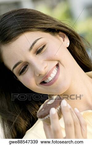 Close-up of a young woman holding a muffin View Large Photo Image Stock Photo - Close-up of a young woman holding a muffin. Fotosearch