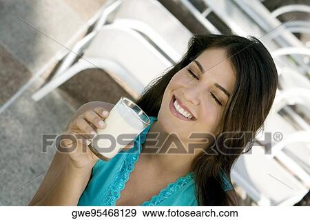 Close-up of a young woman holding a glass of milk View Large Photo Image Stock Photo - Close-up of a young woman holding a glass of milk. Fotosearch