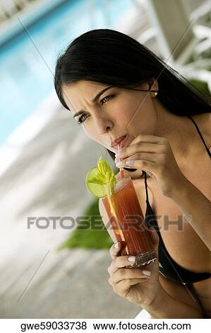 Stock Photo - Close-up of a young woman sipping drink from a glass. Fotosearch