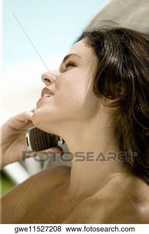 Close-up of a young woman talking on a mobile phone View Large Photo Image Stock Photo - Close-up of a young woman talking on a mobile phone. Fotosearch
