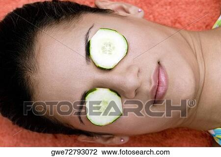 Close-up of a young woman with cucumber slice on her eyes View Large Photo Image Stock Image - Close-up of a young woman with cucumber slice on her eyes. Fotosearch