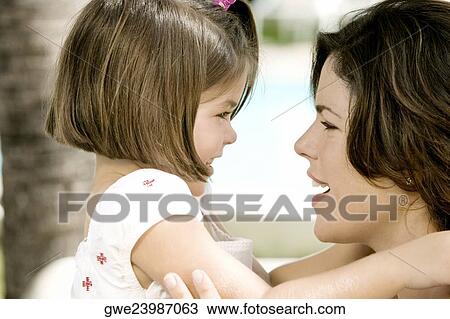 Close-up of a young woman with her daughter smiling View Large Photo Image Stock Image - Close-up of a young woman with her daughter smiling. Fotosearch