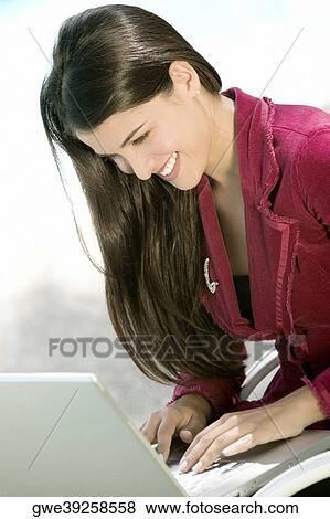 Close-up of a young woman working on a laptop View Large Photo Image Stock Photo - Close-up of a young woman working on a laptop. Fotosearch