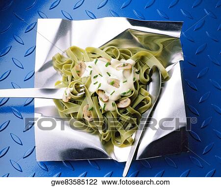 Stock Image - Close-up of tagliatelle with a fork and a spoon on aluminum foil. Fotosearch
