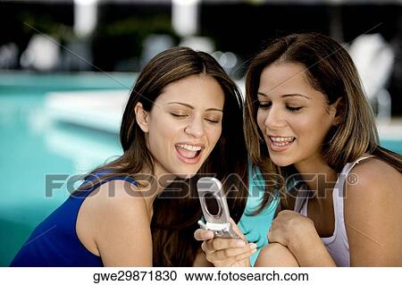 Close-up of two young women holding a mobile phone View Large Photo Image Stock Image - Close-up of two young women holding a mobile phone. Fotosearch