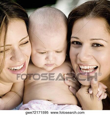 Close-up of two young women holding a baby girl View Large Photo Image Stock Photography - Close-up of two young women holding a baby girl. Fotosearch