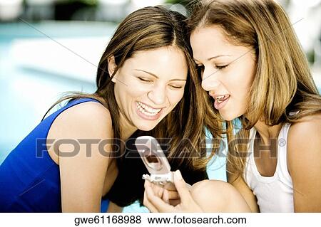 Stock Photo - Close-up of two young women looking at a mobile phone. Fotosearch