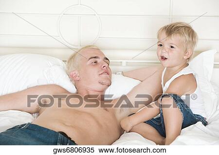 Father lying on the bed looking at his son View Large Photo Image Stock Photography - Father lying on the bed looking at his son. Fotosearch