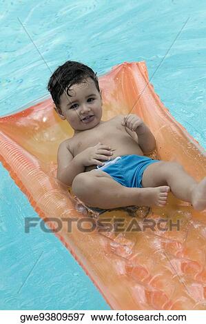 Stock Photo - High angle view of a boy floating on a pool raft. Fotosearch