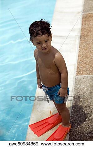 High angle view of a boy standing by the pool View Large Photo Image Stock Photo - High angle view of a boy standing by the pool. Fotosearch