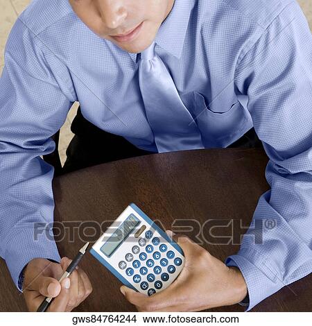 High angle view of a businessman holding a calculator and a pen View Large Photo Image Picture - High angle view of a businessman holding a calculator and a pen. Fotosearch