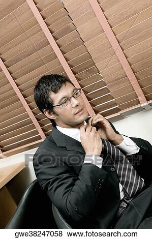 Stock Photo - High angle view of a businessman adjusting his tie. Fotosearch