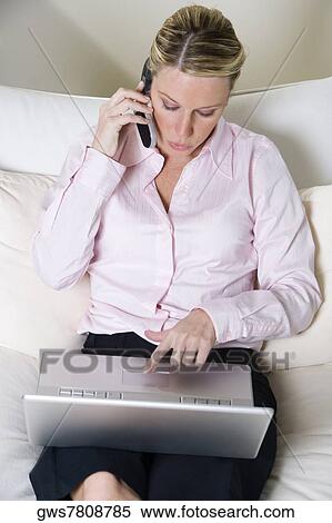 High angle view of a businesswoman talking on a mobile phone while working on a laptop View Large Photo Image Stock Photography - High angle view of a businesswoman talking on a mobile phone while working on a laptop. Fotosearch