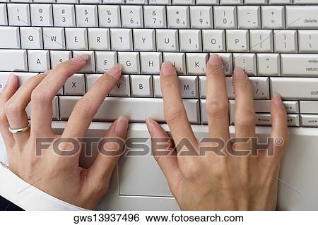 Stock Photograph - High angle view of a businesswoman's hands on a laptop. Fotosearch