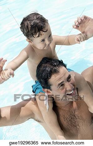 Stock Photography - High angle view of a father carrying his son on his shoulders at a swimming pool. Fotosearch
