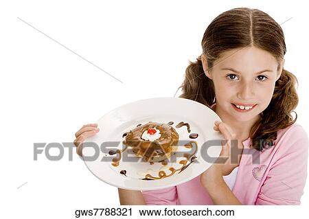 Stock Image - High angle view of a girl holding dessert in a plate. Fotosearch