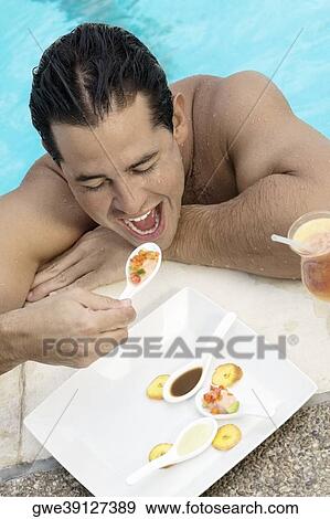 Stock Photo - High angle view of a young man eating food. Fotosearch