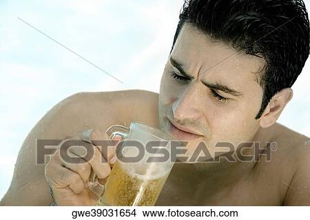High angle view of a young man holding a mug of beer View Large Photo Image Picture - High angle view of a young man holding a mug of beer. Fotosearch
