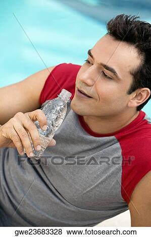 High angle view of a young man holding a water bottle View Large Photo Image Stock Photo - High angle view of a young man holding a water bottle. Fotosearch