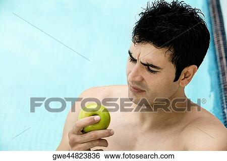 High angle view of a young man holding an apple View Large Photo Image Stock Photograph - High angle view of a young man holding an apple. Fotosearch