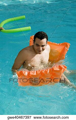 Stock Photo - High angle view of a young man sitting on a pool raft in a swimming pool. Fotosearch