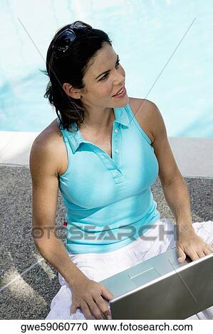Stock Image - High angle view of a young woman holding a laptop. Fotosearch