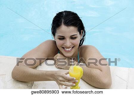 High angle view of a young woman holding a drink in a swimming pool View Large Photo Image Stock Image - High angle view of a young woman holding a drink in a swimming pool. Fotosearch