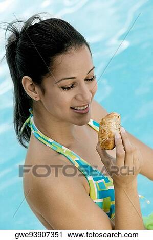 Stock Image - High angle view of a young woman holding a bun. Fotosearch