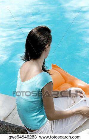 High angle view of a young woman sitting by the pool View Large Photo Image Stock Image - High angle view of a young woman sitting by the pool. Fotosearch