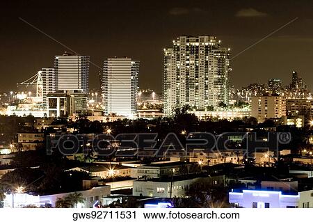 Stock Image - High angle view of buildings in a city lit up at night. Fotosearch
