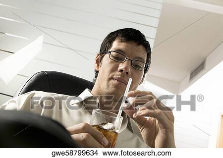 Low angle view of a businessman holding a drink View Large Photo Image Picture - Low angle view of a businessman holding a drink. Fotosearch