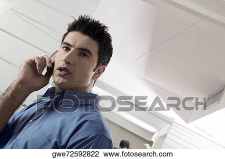 Stock Image - Low angle view of a businessman using a mobile phone. Fotosearch