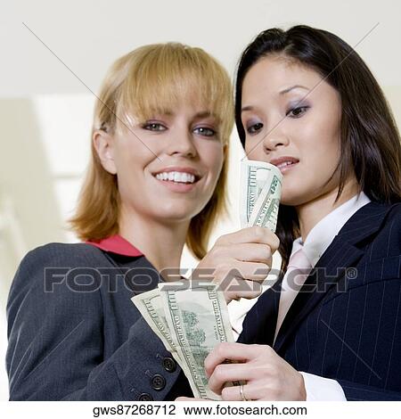 Low angle view of a businesswoman showing a dollar bill to another businesswoman View Large Photo Image Stock Image - Low angle view of a businesswoman showing a dollar bill to another businesswoman. Fotosearch