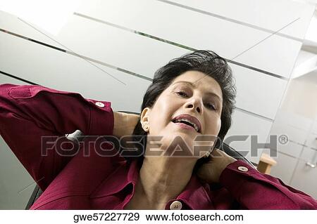 Low angle view of a businesswoman with hands behind head View Large Photo Image Stock Photo - Low angle view of a businesswoman with hands behind head. Fotosearch