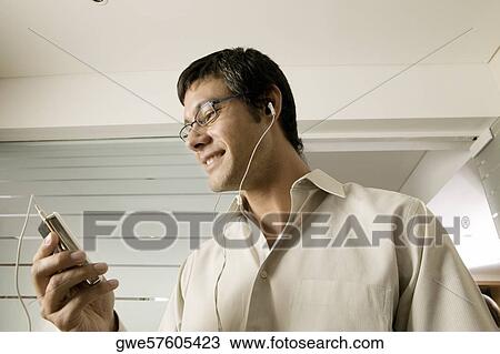 Low angle view of a mid adult man listening to an MP3 Player View Large Photo Image Stock Image - Low angle view of a mid adult man listening to an MP3 Player. Fotosearch